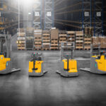 Żółte wózki widłowe usatwione w rzędzie, w magazynie